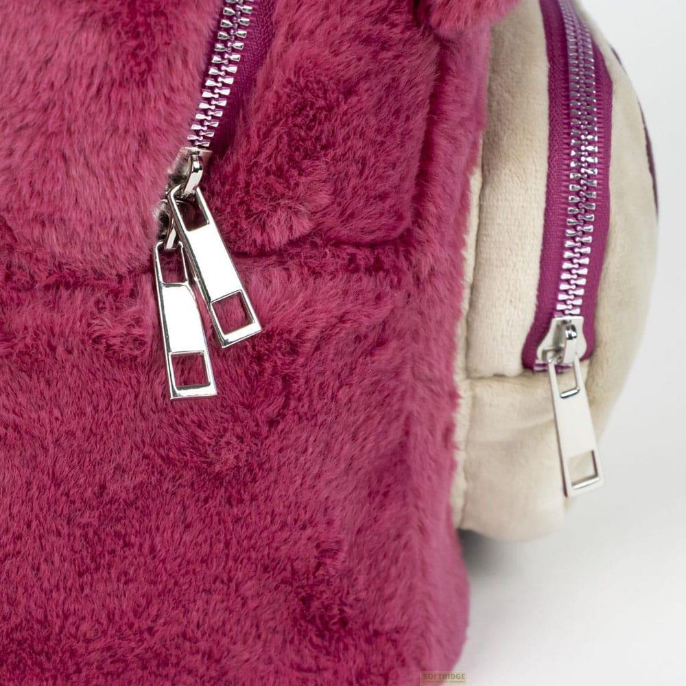 Primer plano de un bolso magenta esponjoso con cremalleras plateadas.