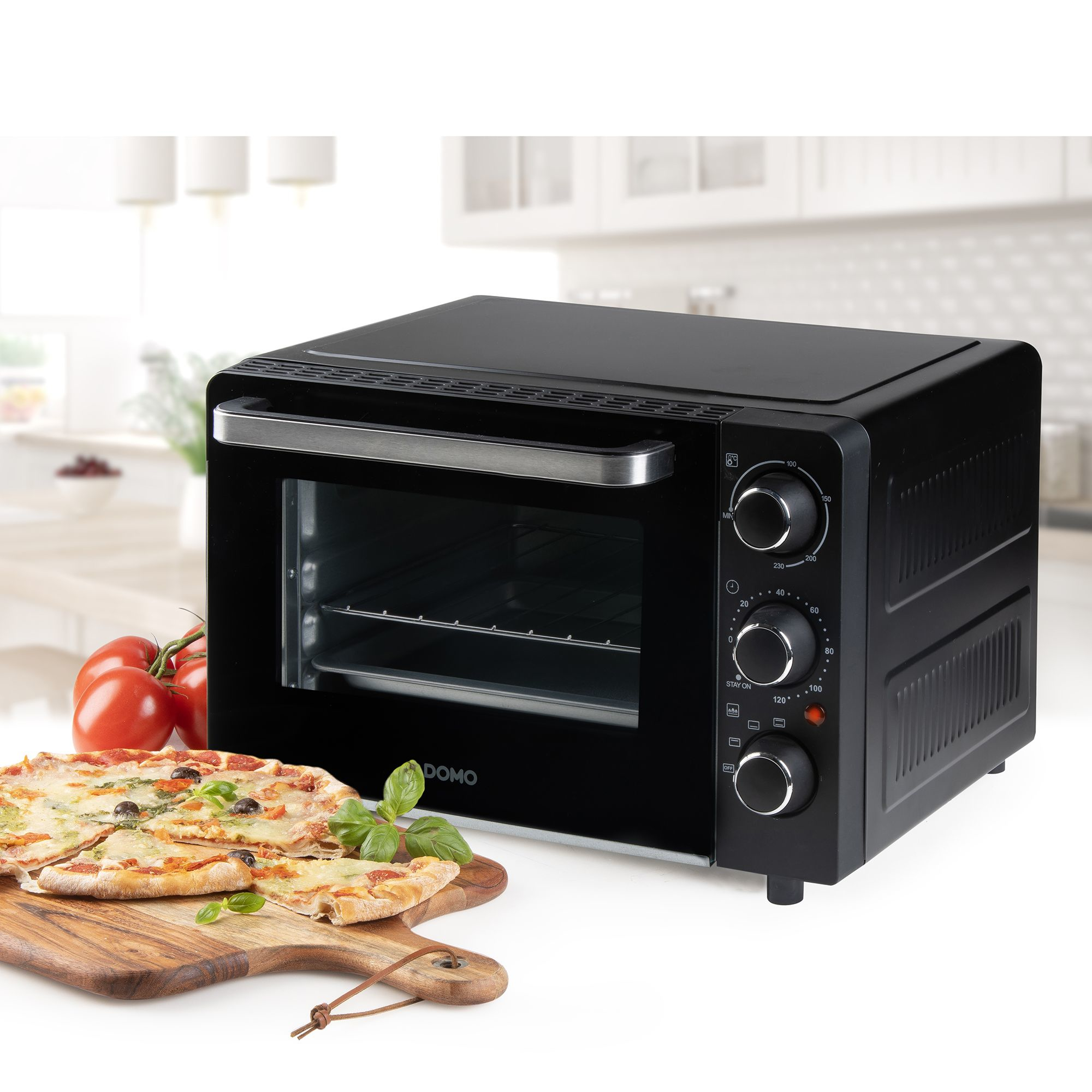 Schwarzer Ofen mit Pizza, Tomaten und Kräutern auf einem Holzbrett.