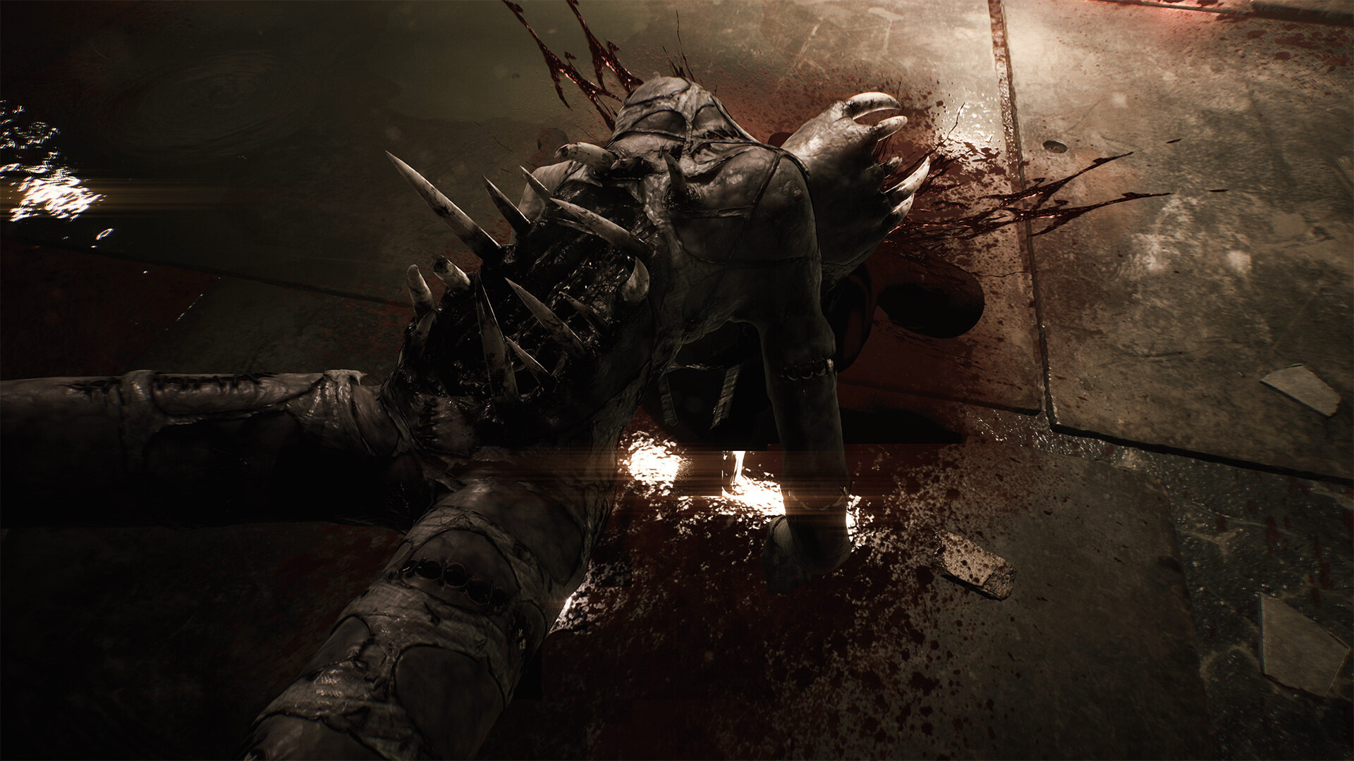 Krwawa istota z kolcami leży na brudnej podłodze.