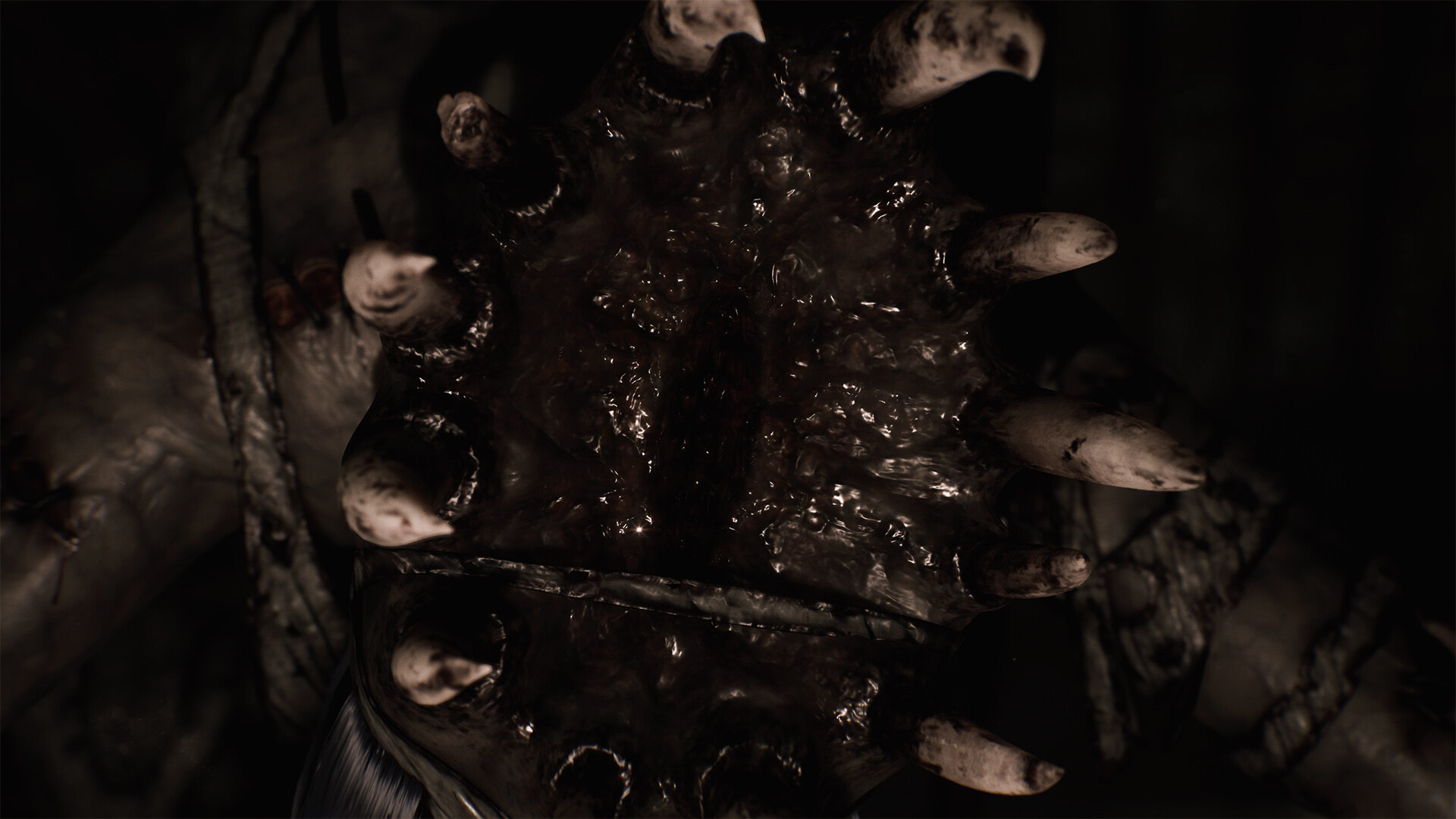 Zbliżenie ciemnej, śliskiej dłoni stwora z zaostrzonymi palcami.