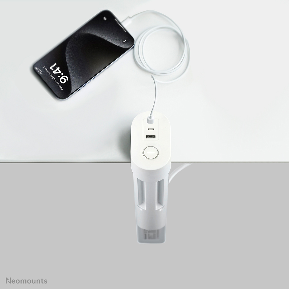 Un cavo di ricarica bianco collega uno smartphone a un caricabatterie bianco con porte USB.