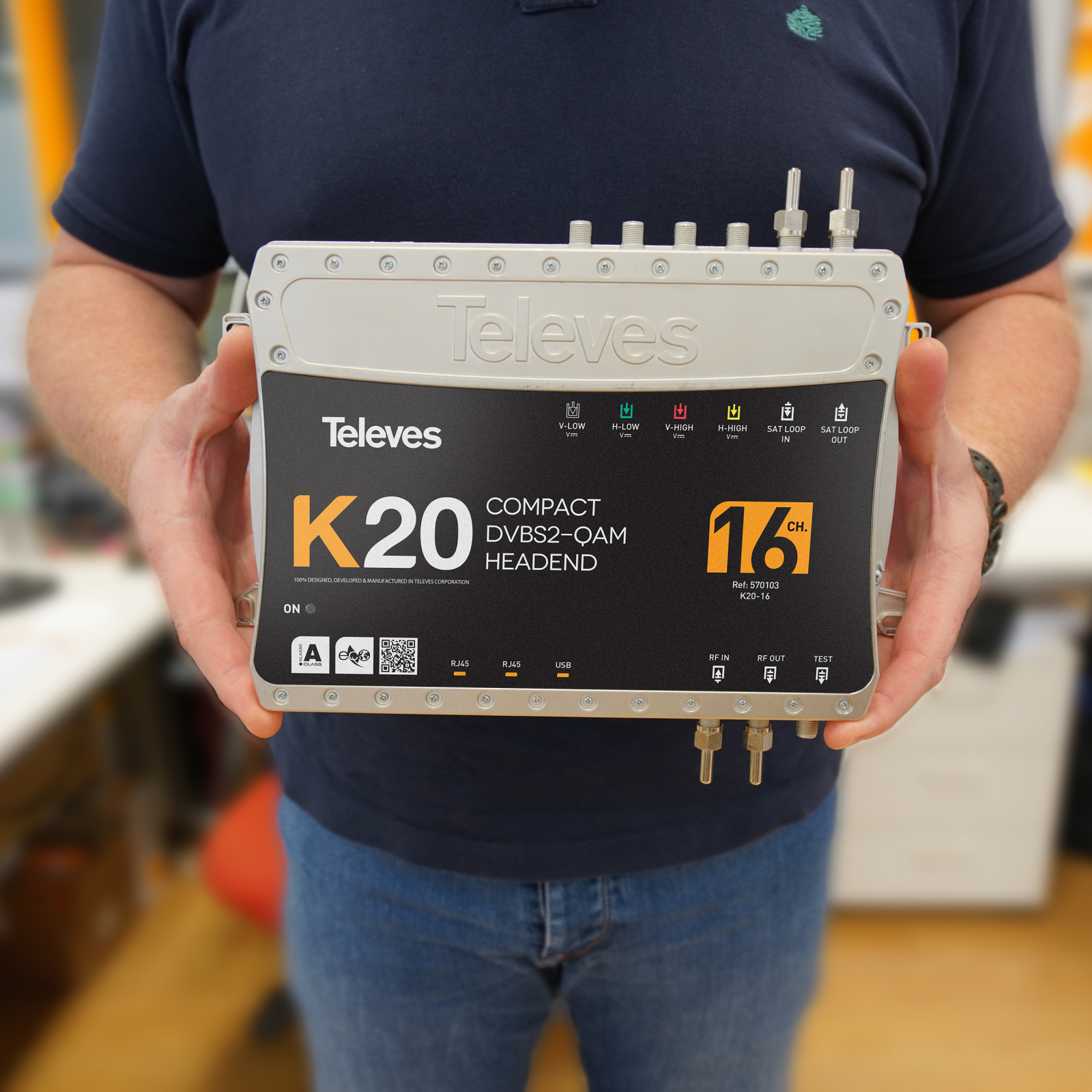 Uomo tiene un dispositivo Televes K20 DVB-S2/QAM con connettori ed etichette.