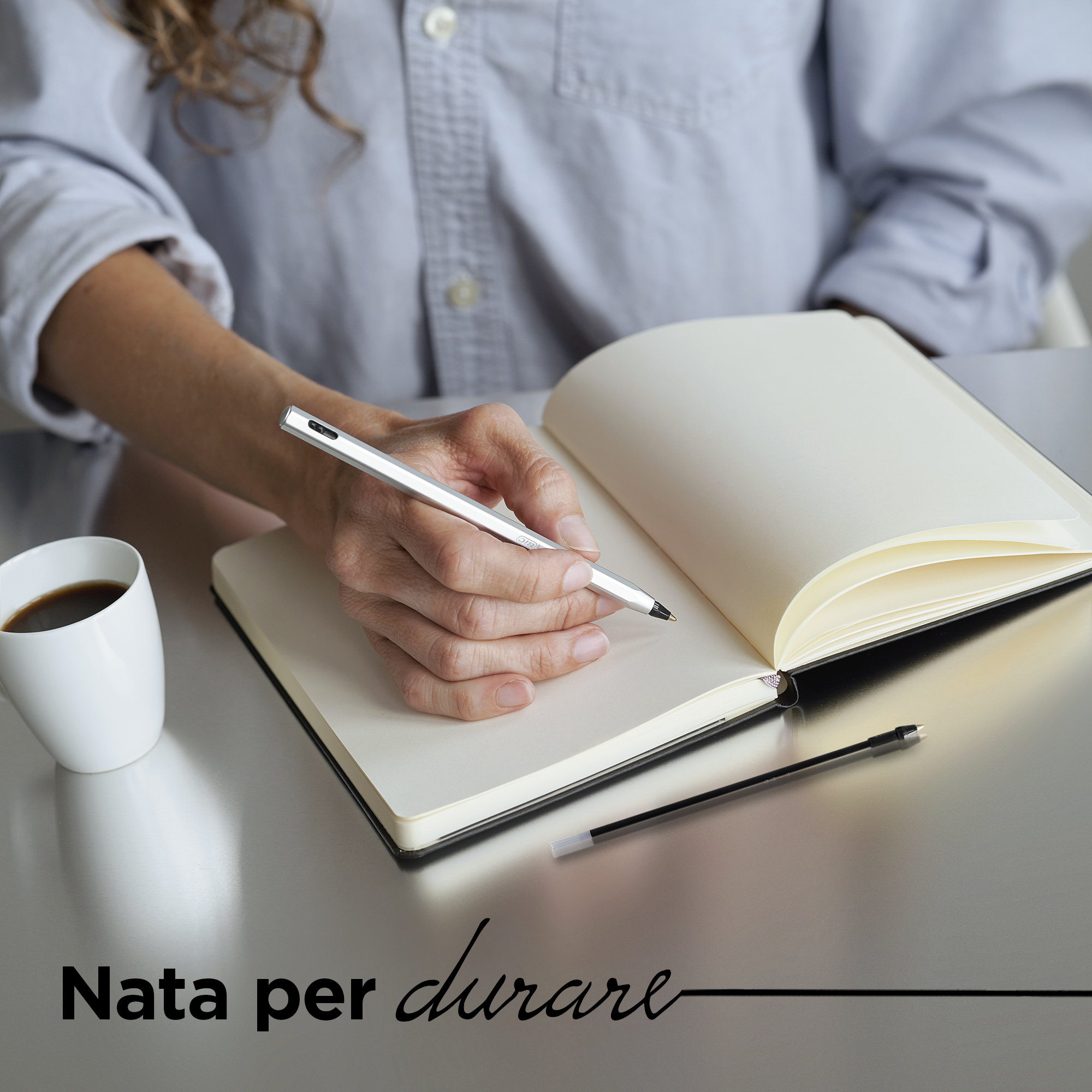 Una persona scrive su un taccuino, con una tazza di caffè e una penna vicine.