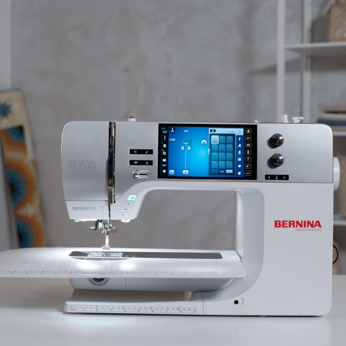 Una máquina de coser Bernina plateada y blanca con pantalla táctil y aguja.