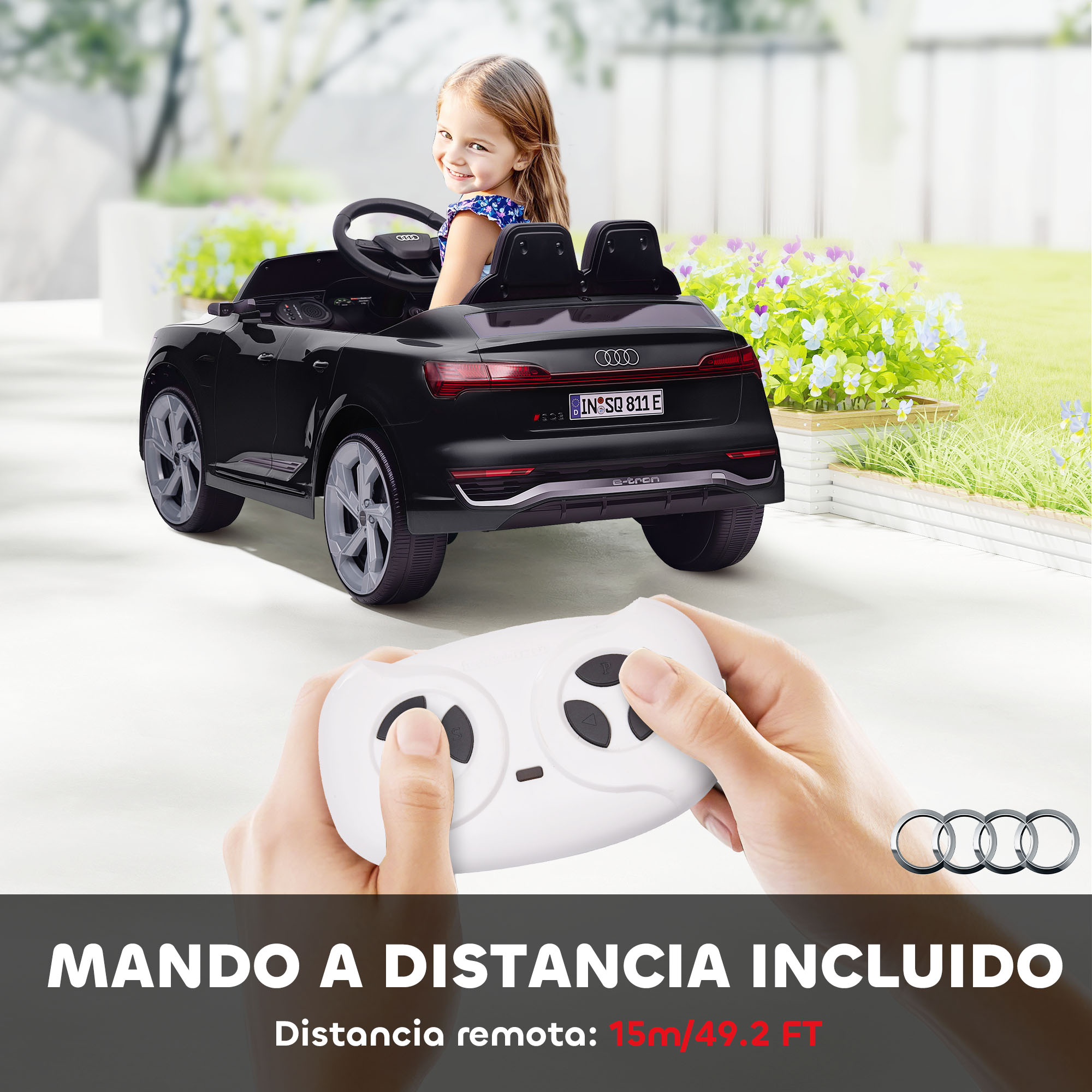 Una niña sentada en un coche de juguete Audi negro, controlado por control remoto.