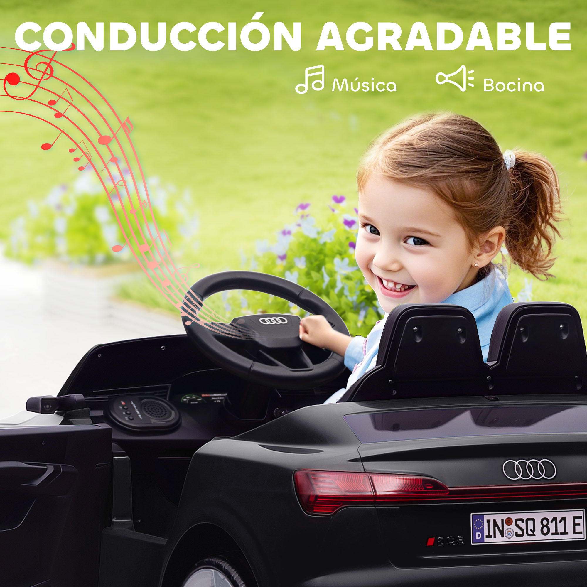 Una niña conduce un coche de juguete Audi negro al aire libre.