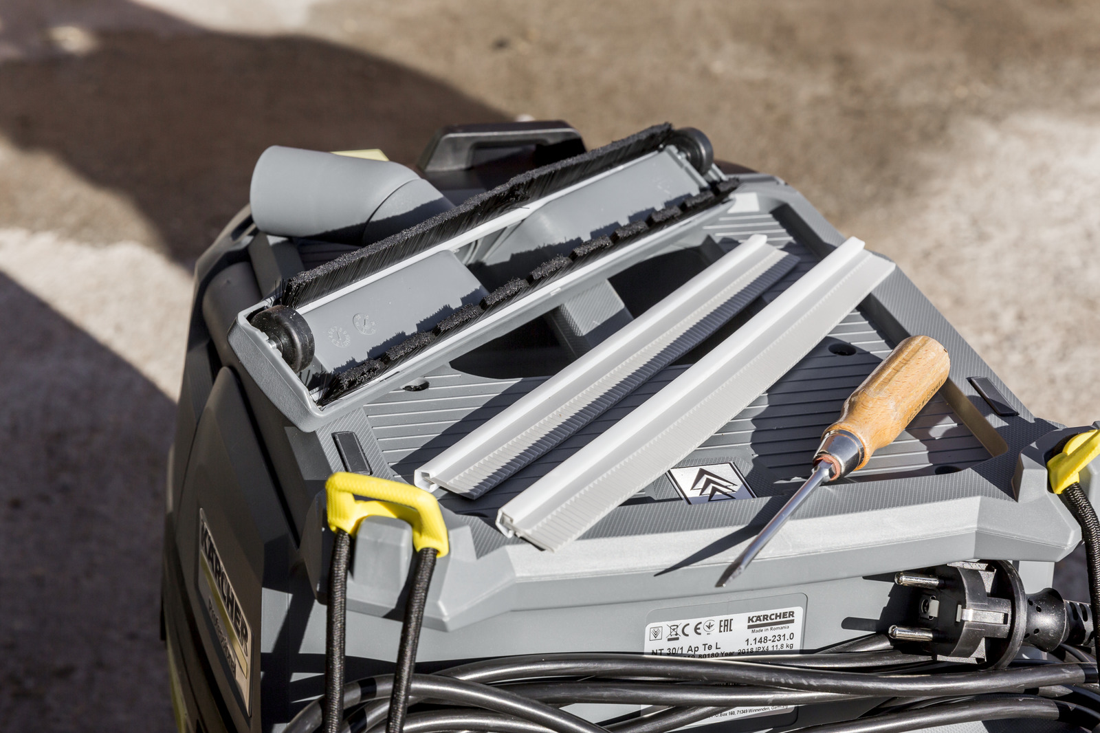 Gray Karcher vacuum cleaner with brush attachment, screwdriver, and cord.
