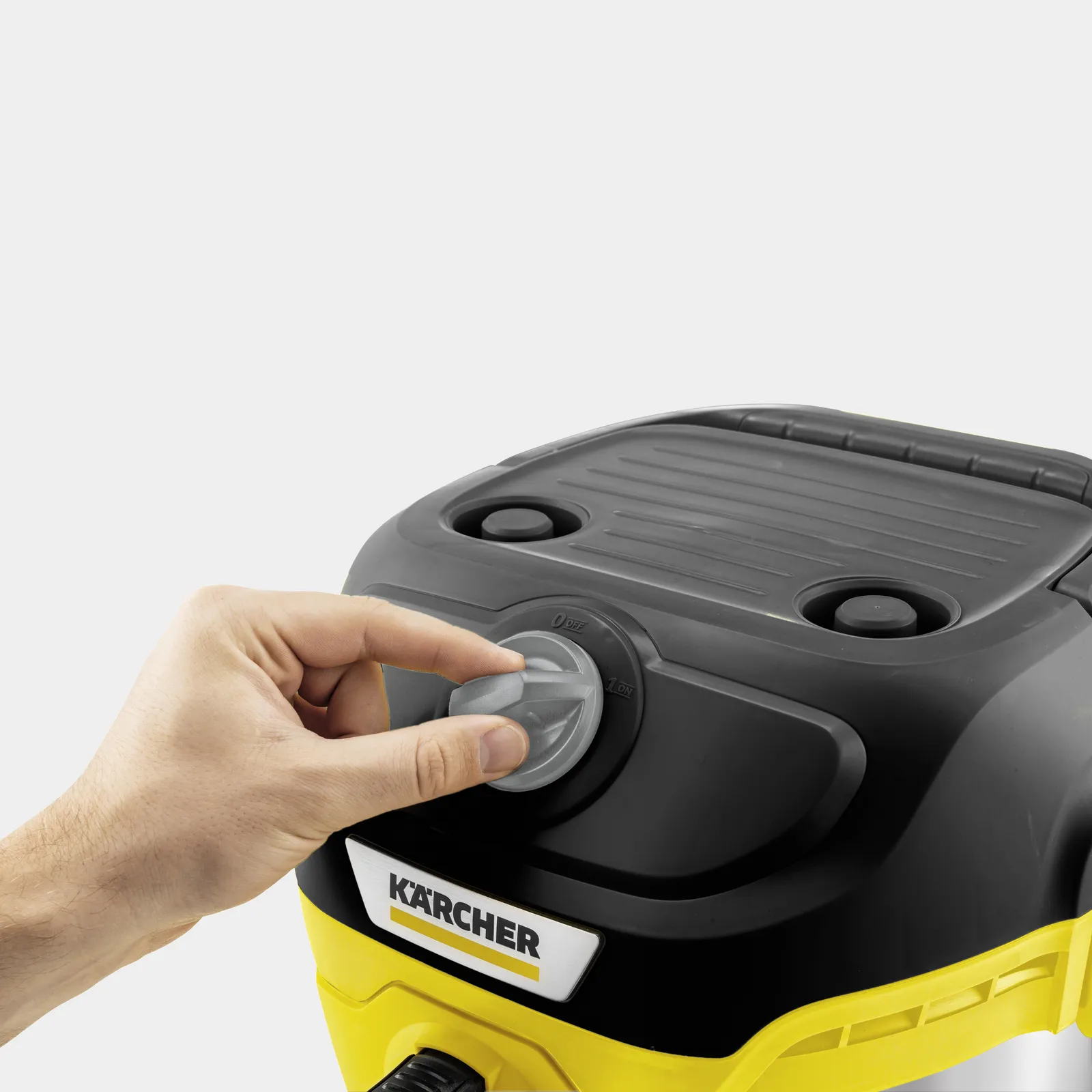 Ręka przekręca szary pokrętło na czarno-żółtym urządzeniu Kärcher.