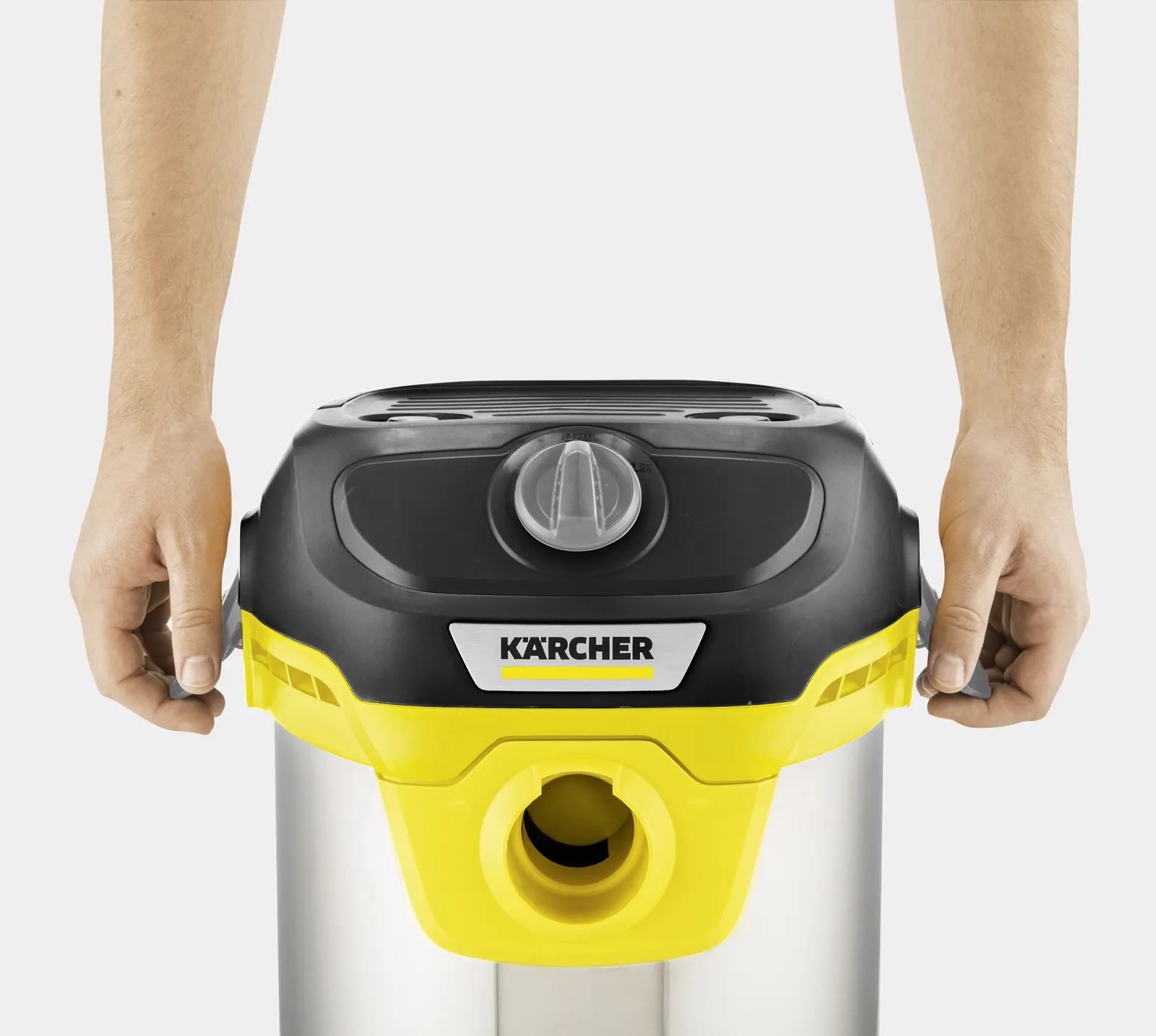 Ręce trzymające odkurzacz Kärcher do pracy na mokro i sucho. Żółty i czarny ze srebrnym zbiornikiem.