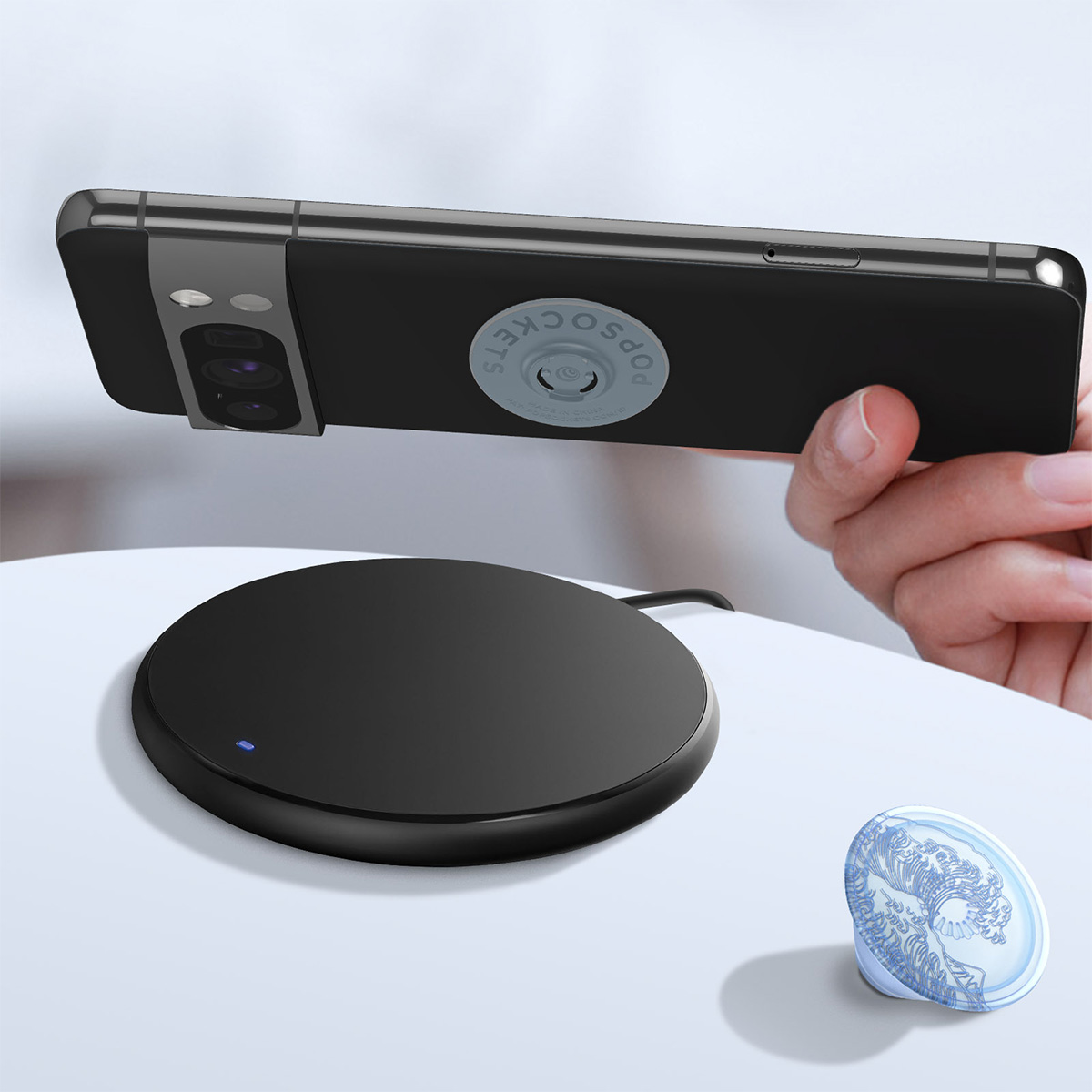 Smartphone nero con PopSocket in carica su base di ricarica nera.