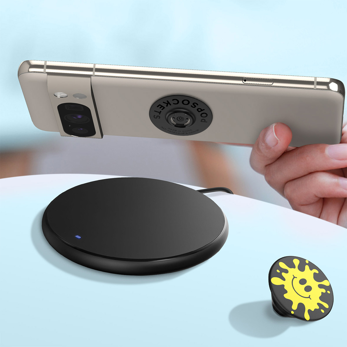 Un telefono con PopSocket è tenuto sopra un caricatore wireless nero.