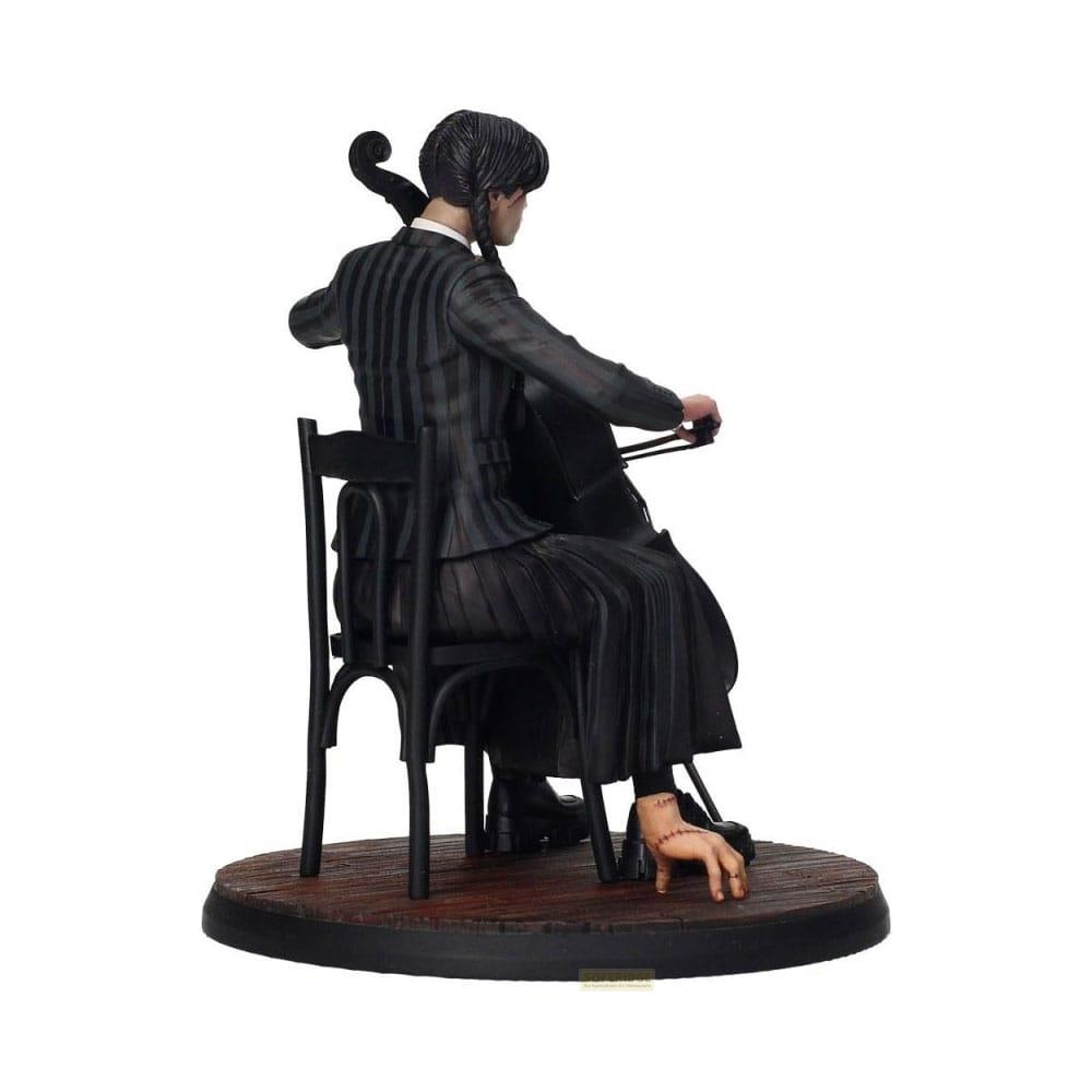 Figura de una persona tocando el violonchelo, sentada en una silla sobre una base de madera.