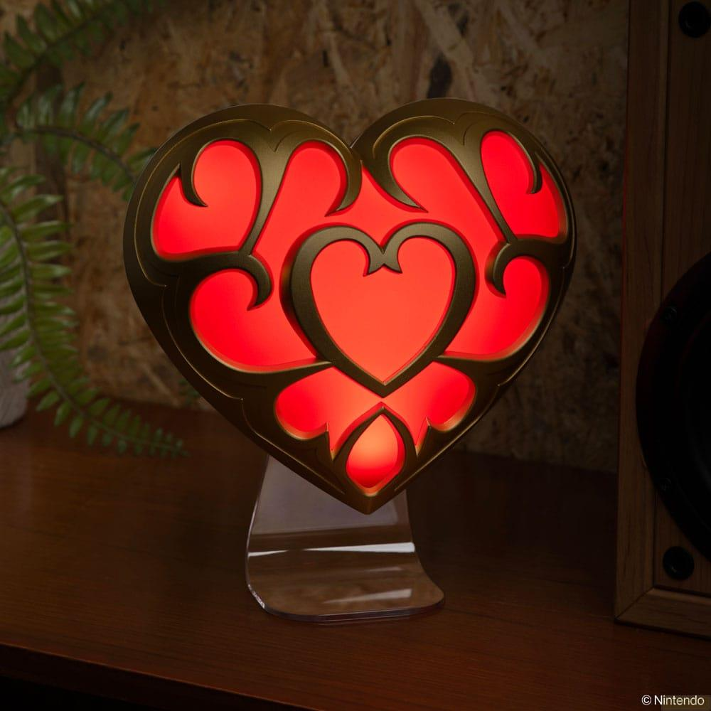 Un objeto en forma de corazón con luz roja y borde dorado se apoya en un soporte.