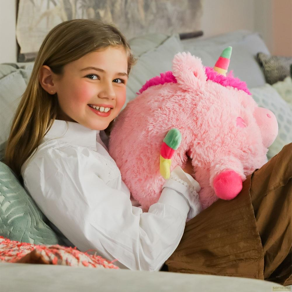 Ein Mädchen mit einem rosa Einhorn-Stofftier auf einem Sofa.