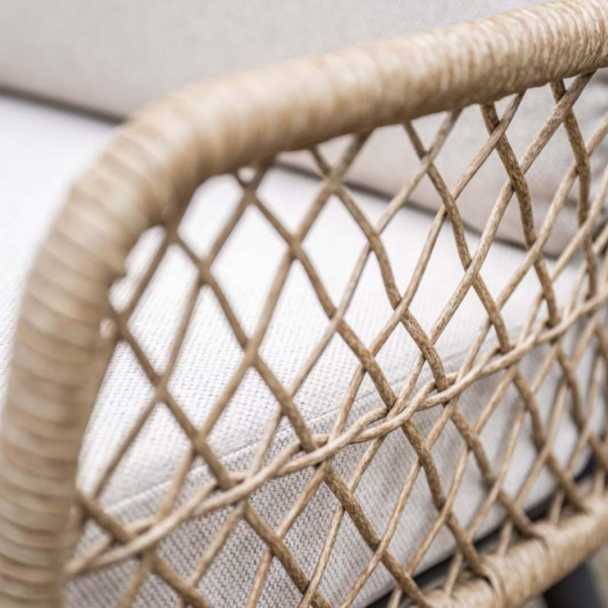 Gros plan d'une chaise en osier tressé avec coussin en tissu clair à l'arrière.