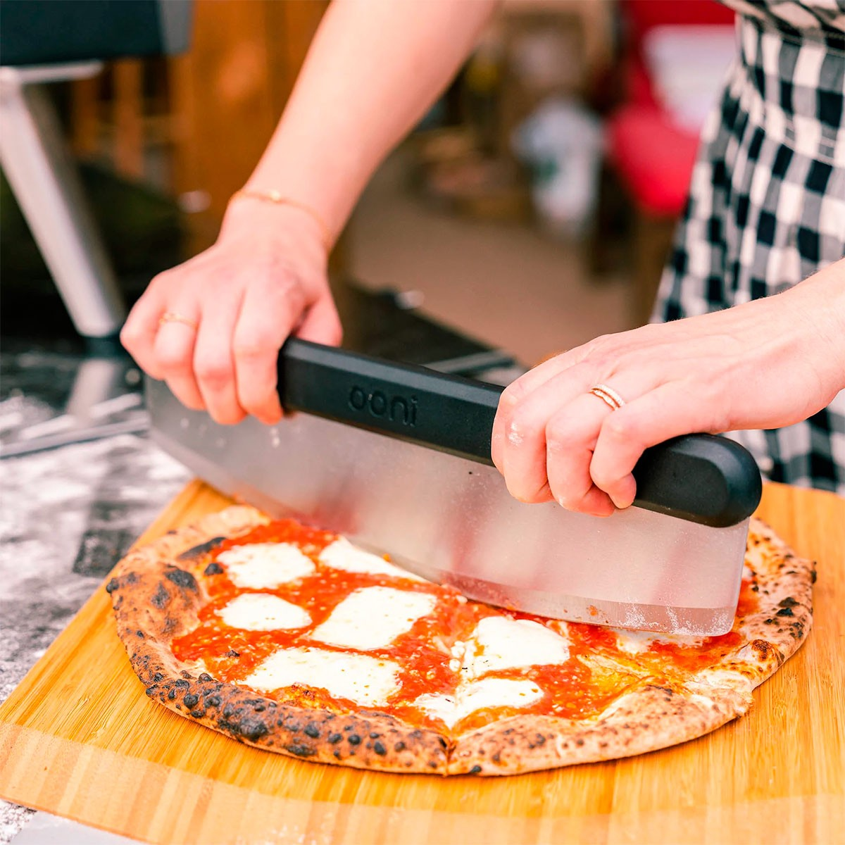 Una pizza viene tagliata su un tagliere di legno con un tagliapizza.