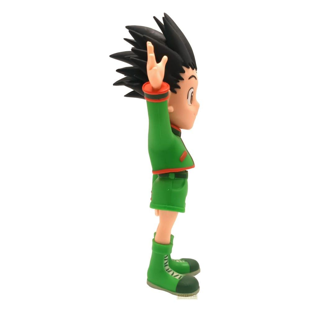 Una figura verde con capelli neri alza una mano. La figura indossa abiti verdi.
