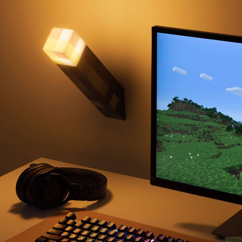 Eine Minecraft-Fackel-Lampe beleuchtet eine Wand neben einem Monitor mit Spielgrafik.
