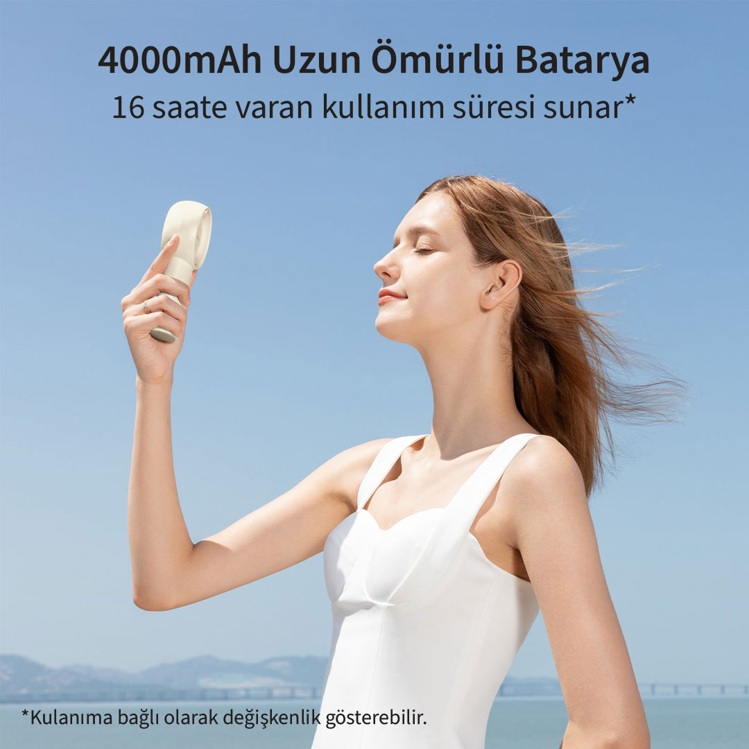 Une femme tient un ventilateur blanc sous un ciel bleu, face à la mer.