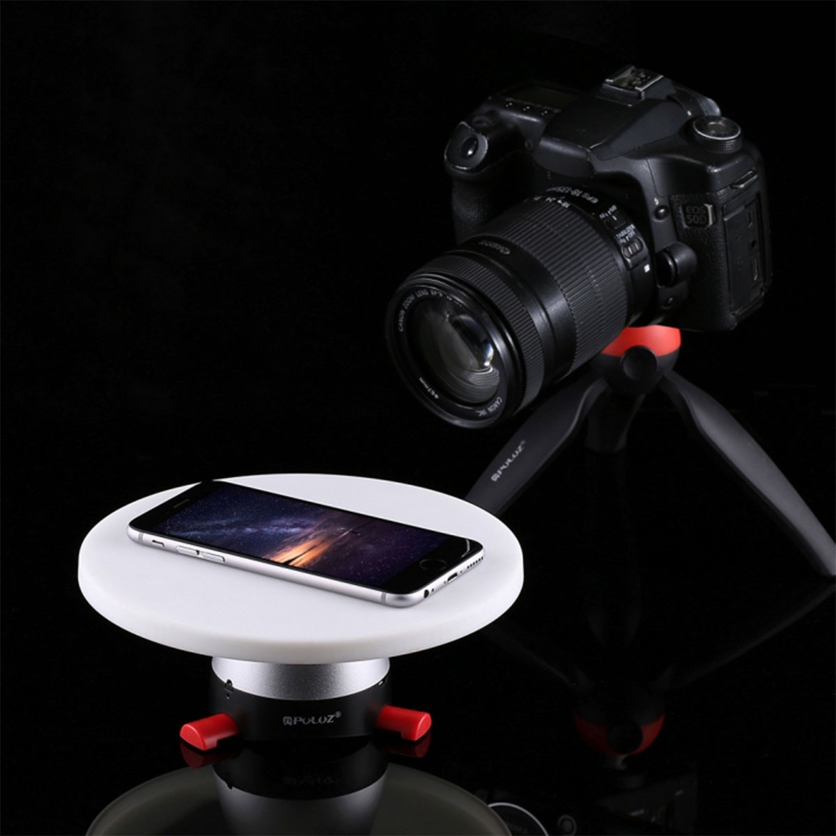 Uno smartphone poggia su un piatto girevole bianco accanto a una fotocamera su treppiede.