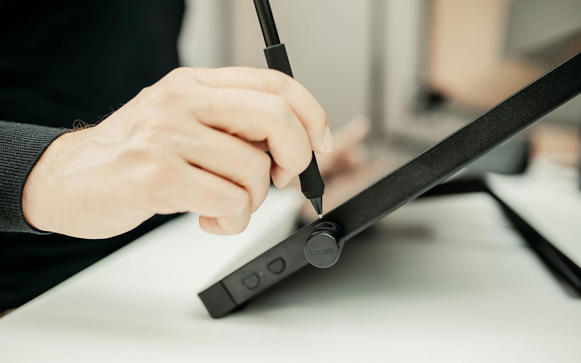 Eine Hand hält einen Stift und zeichnet auf einem schwarzen Tablet.