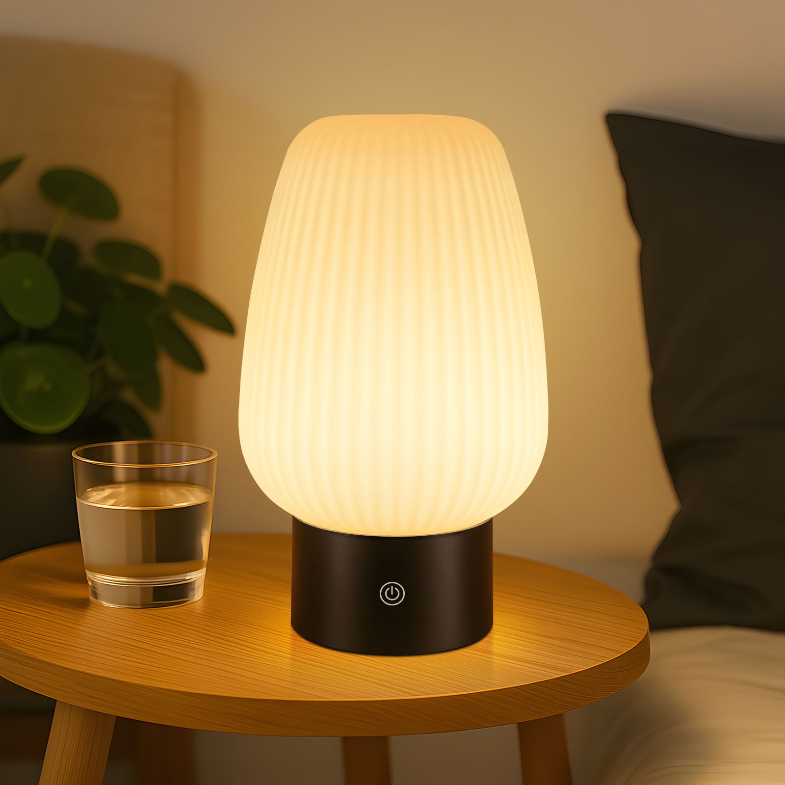 Świecąca lampka nocna z prążkowanym kloszem obok szklanki wody.