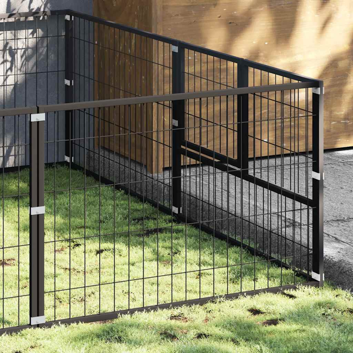 Ein dunkler Metallzaun mit quadratischem Gitter steht auf einem Rasen vor einem Holzgebäude.