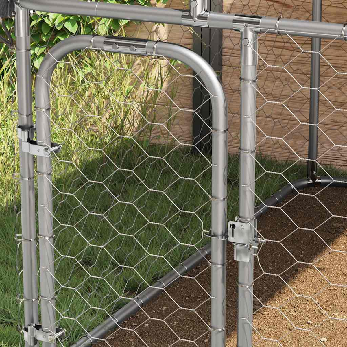 Ein Metalltor mit Hühnerdrahtgeflecht, in einer grasbewachsenen Fläche mit Holzzaun.
