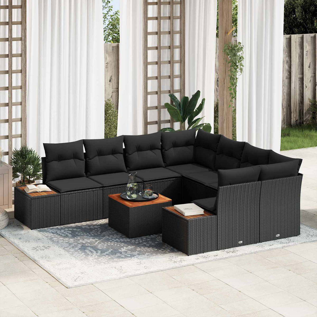 Ein schwarzes Rattangeflecht-Ecksofa mit Kissen und Holztischen auf einer Terrasse.