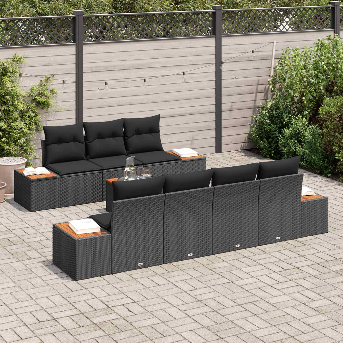 Dunkelgraue Lounge-Möbel mit schwarzen Kissen auf einer gepflasterten Terrasse.