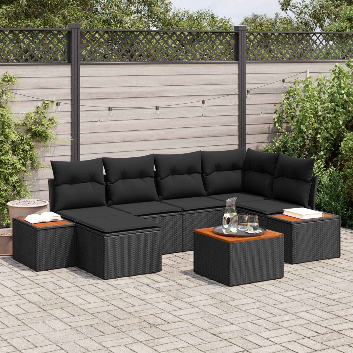 Draußen-Lounge-Set mit schwarzen Kissen und Holztischen auf gepflastertem Hof.
