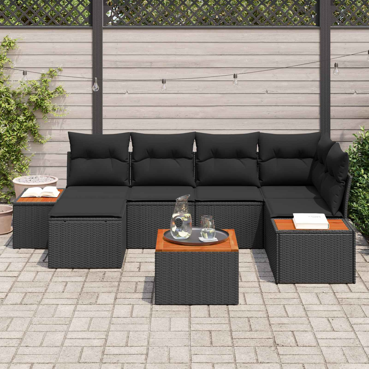 Outdoor-Lounge mit schwarzen Kissen, Holztischen und Lichtern.