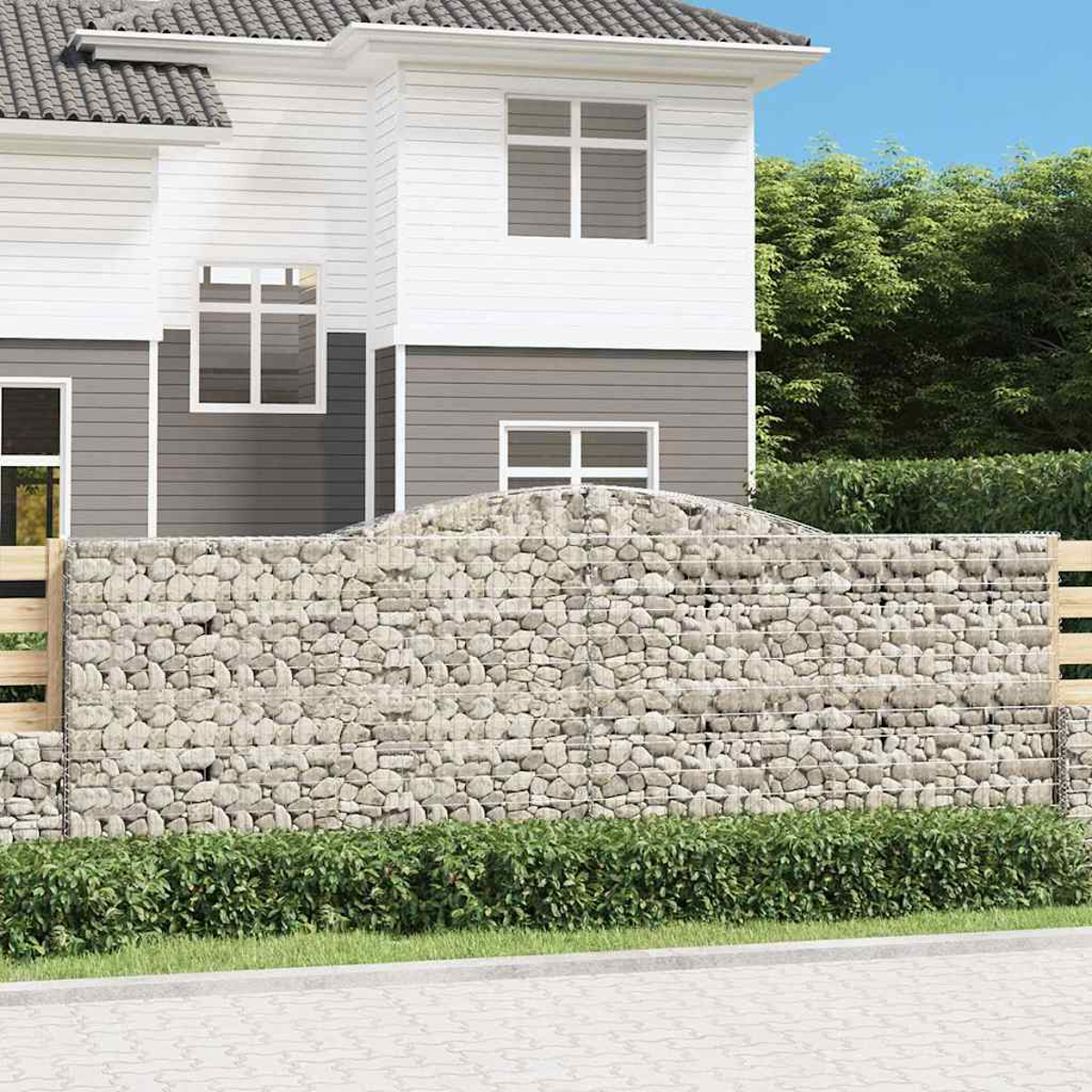 Ein zweistöckiges Haus mit Steinmauer und Grünanlage.