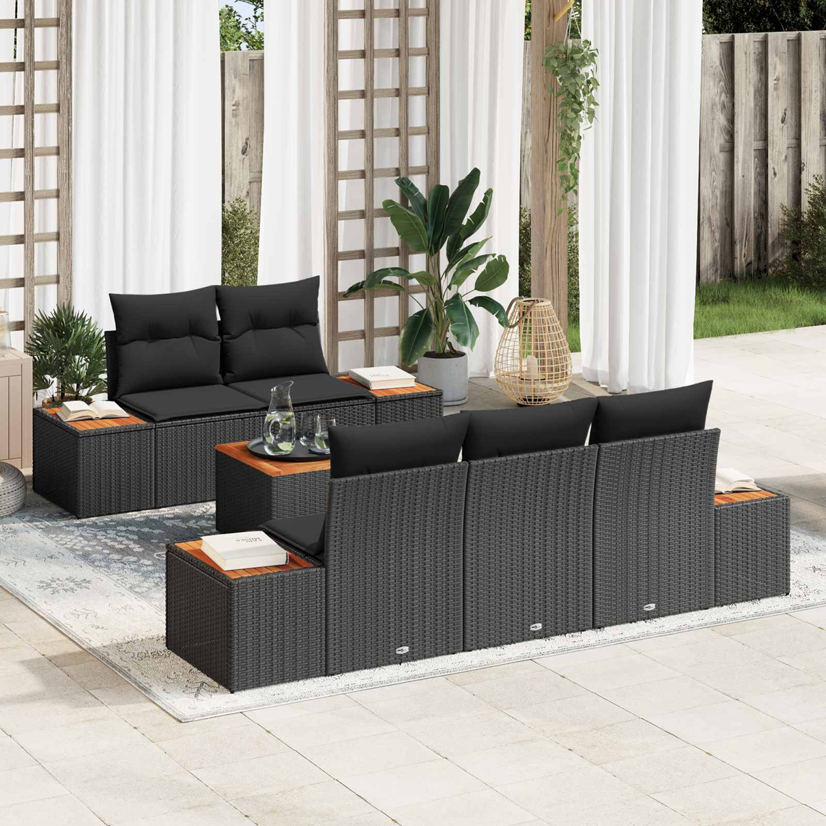 Muebles de salón de ratán gris oscuro con cojines negros en un patio.