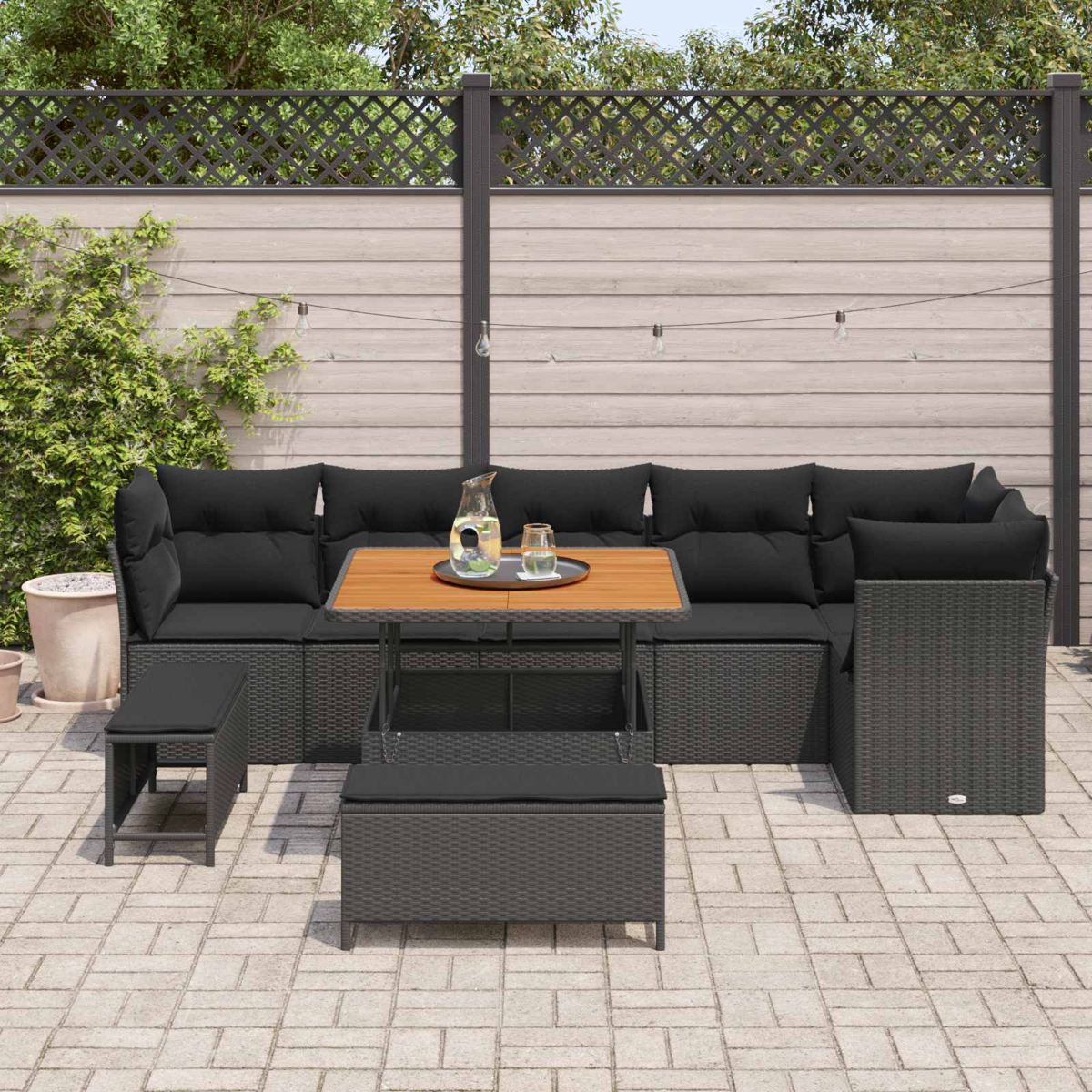 Eine anthrazitfarbene Rattan-Ecklounge mit schwarzen Kissen und Holztisch.