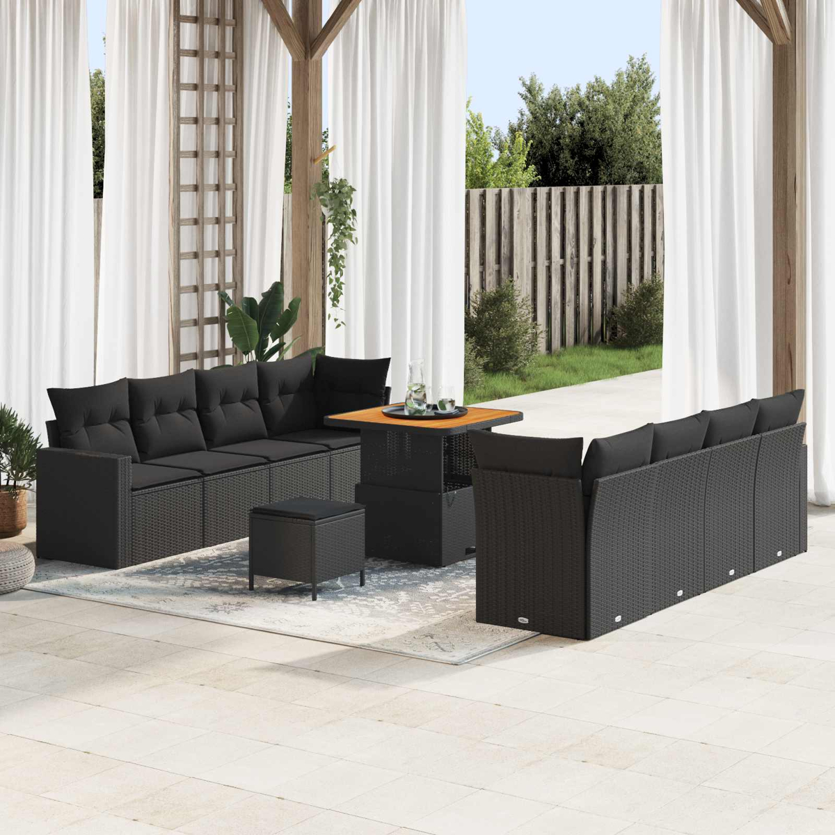 Ein Outdoor-Lounge-Set aus schwarzem Rattan mit Sofas, Tisch und Hocker.