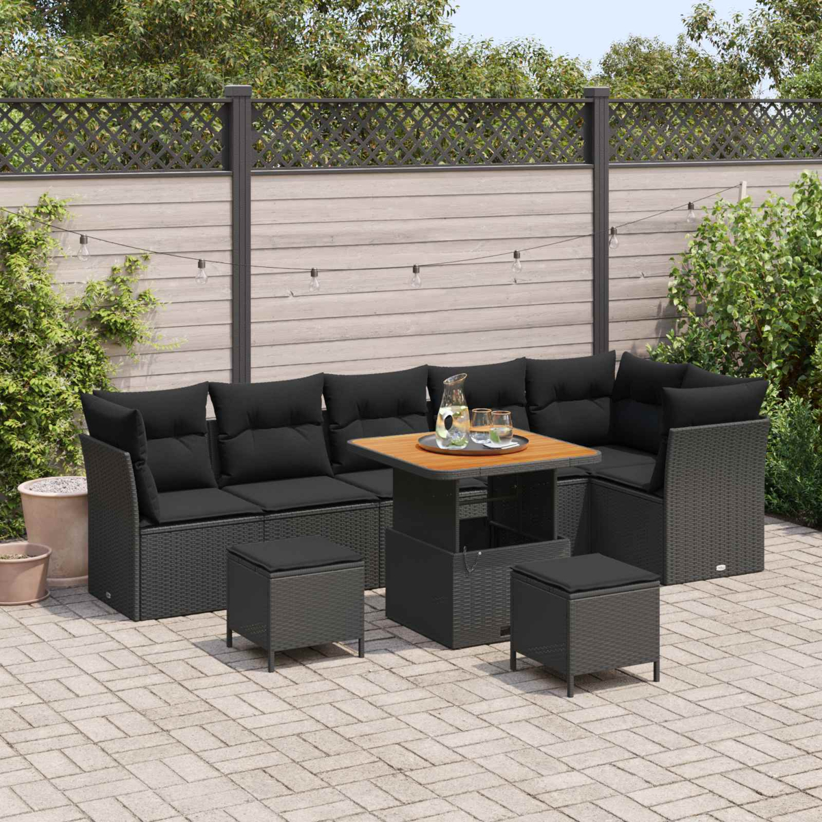 Dunkelgraue Lounge-Garnitur mit schwarzen Kissen und ausziehbarem Tisch auf Kopfsteinpflaster.