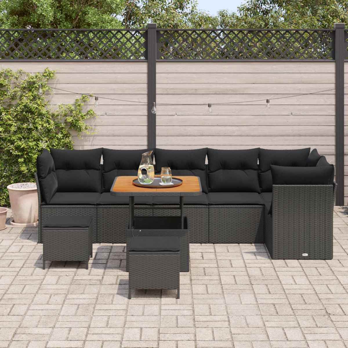 Dunkle Lounge-Garnitur mit Kissen und Beistelltisch auf einer gepflasterten Terrasse.