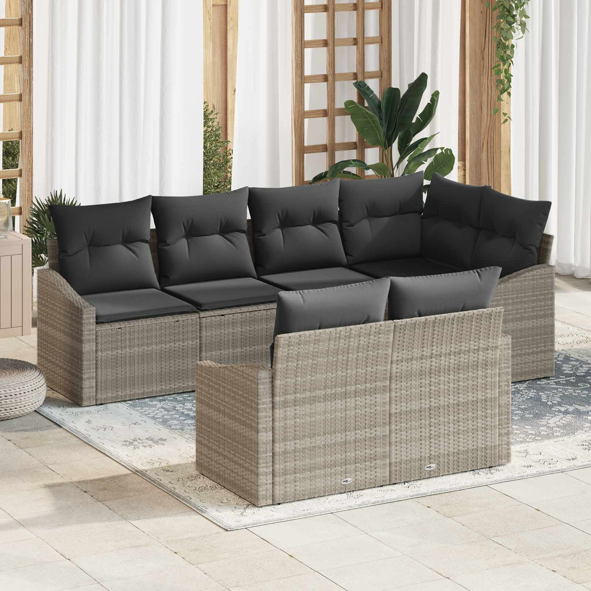 Graues Rattan-Lounge-Set mit schwarzen Kissen auf einer Terrasse.