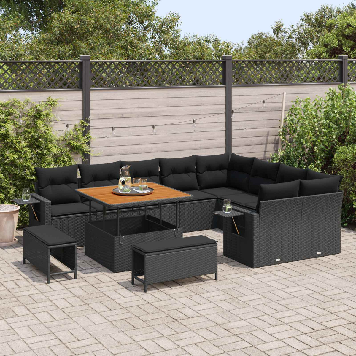 Muebles de exterior de ratán oscuro con cojines negros y mesa de madera.