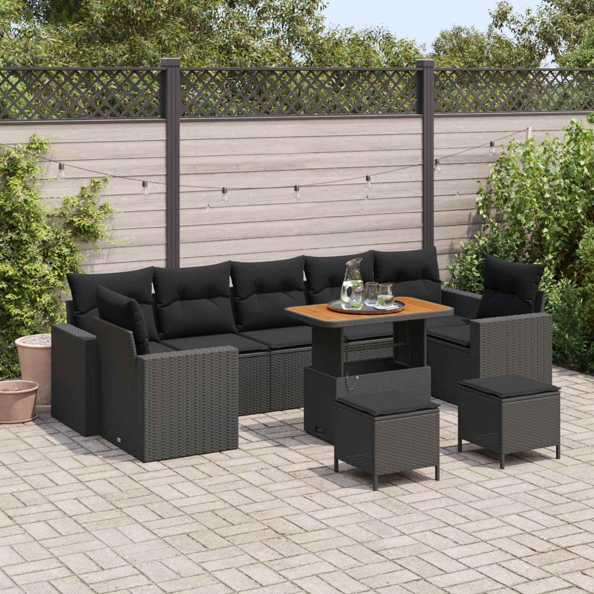 Dunkelgraue Rattan-Lounge mit schwarzen Kissen und einem höhenverstellbaren Tisch.