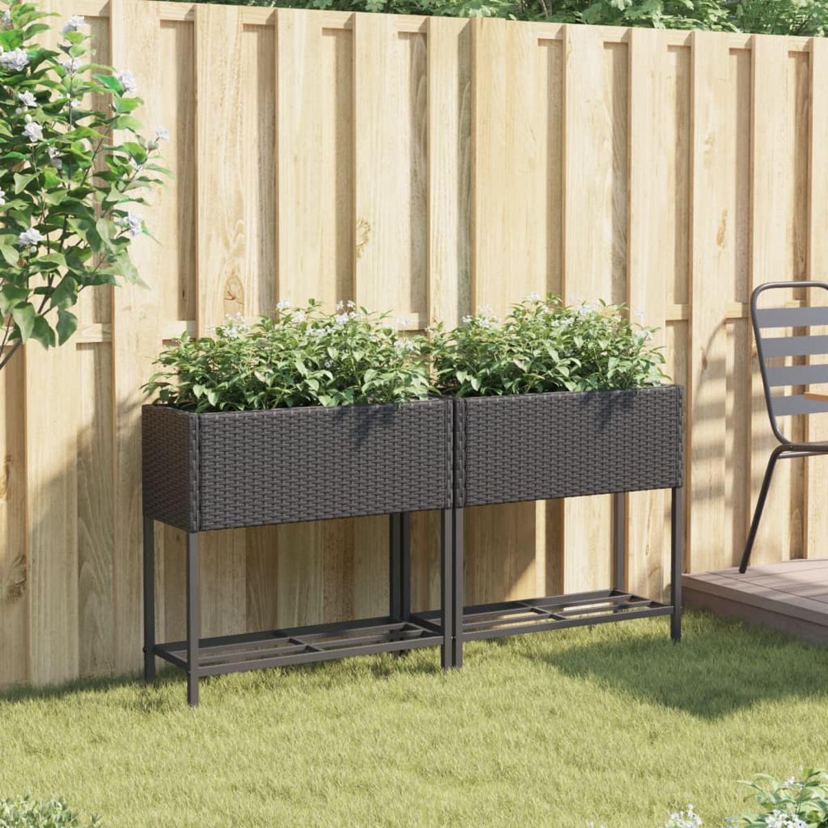 Due fioriere rettangolari effetto rattan scuro con piante davanti a una recinzione di legno.