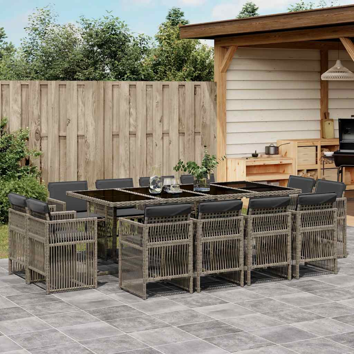 Ein großer Outdoor-Esstisch mit 10 Stühlen, daneben ein Grill und Holzregale.