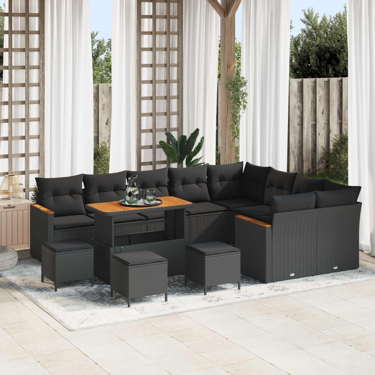 Dunkelgraue Lounge-Garnitur mit Kaffeetisch und Hockern auf einer hellen Terrasse.