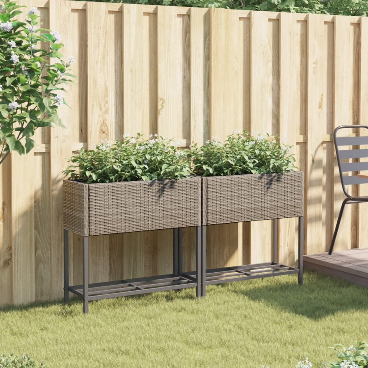 Due fioriere rettangolari effetto rattan con piante, davanti a una recinzione in legno.
