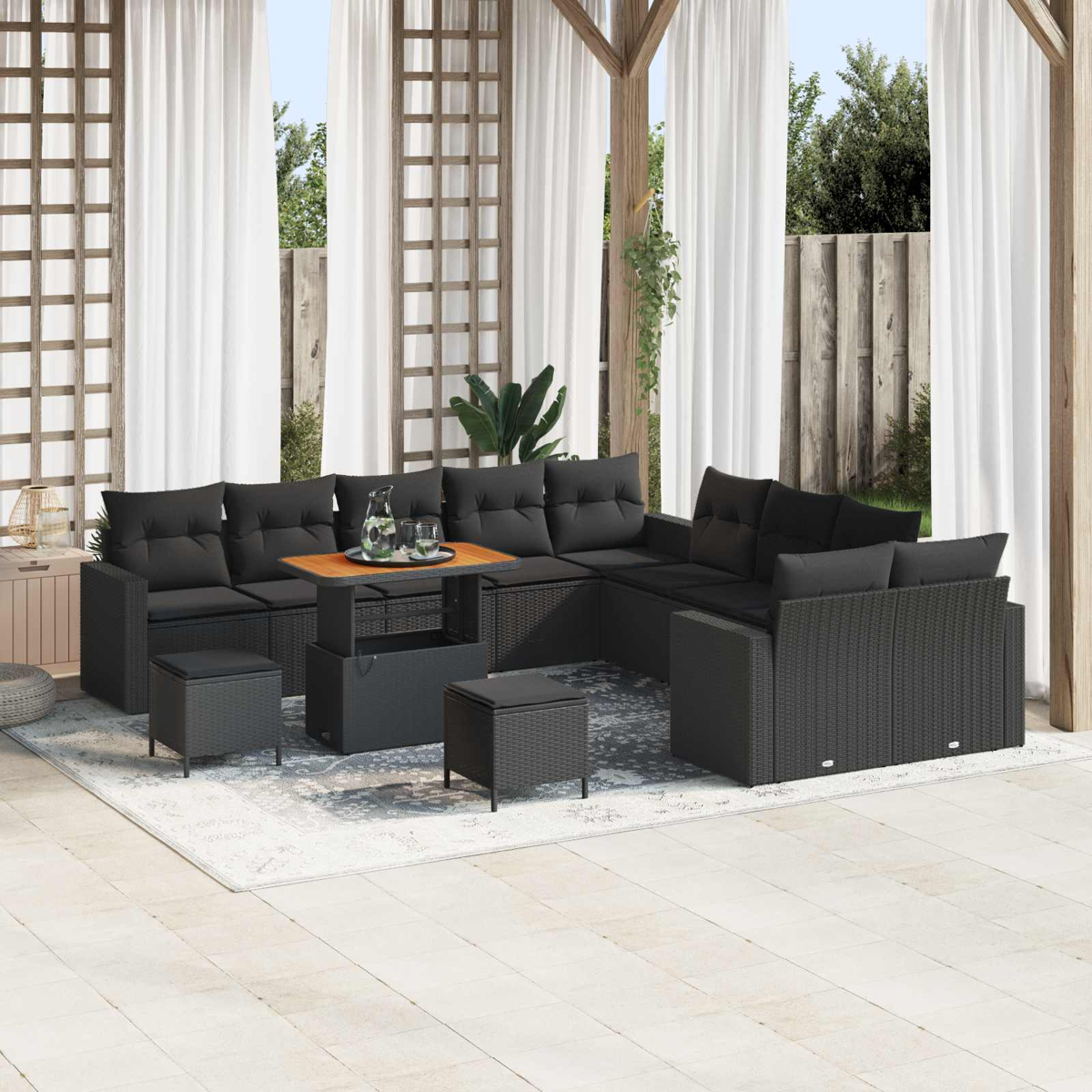 Dunkelgraue Lounge-Garnitur mit Kissen auf einer Terrasse mit weißem Teppich.