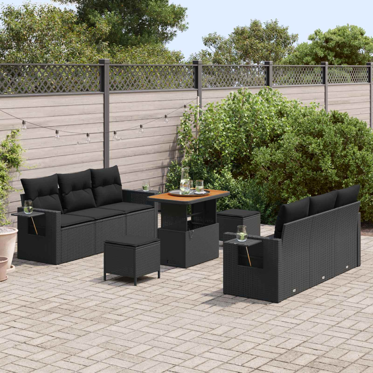 Ein moderner Outdoor-Sitzbereich mit schwarzen Korbmöbeln, darunter ein Sofa, ein Tisch und Hocker.