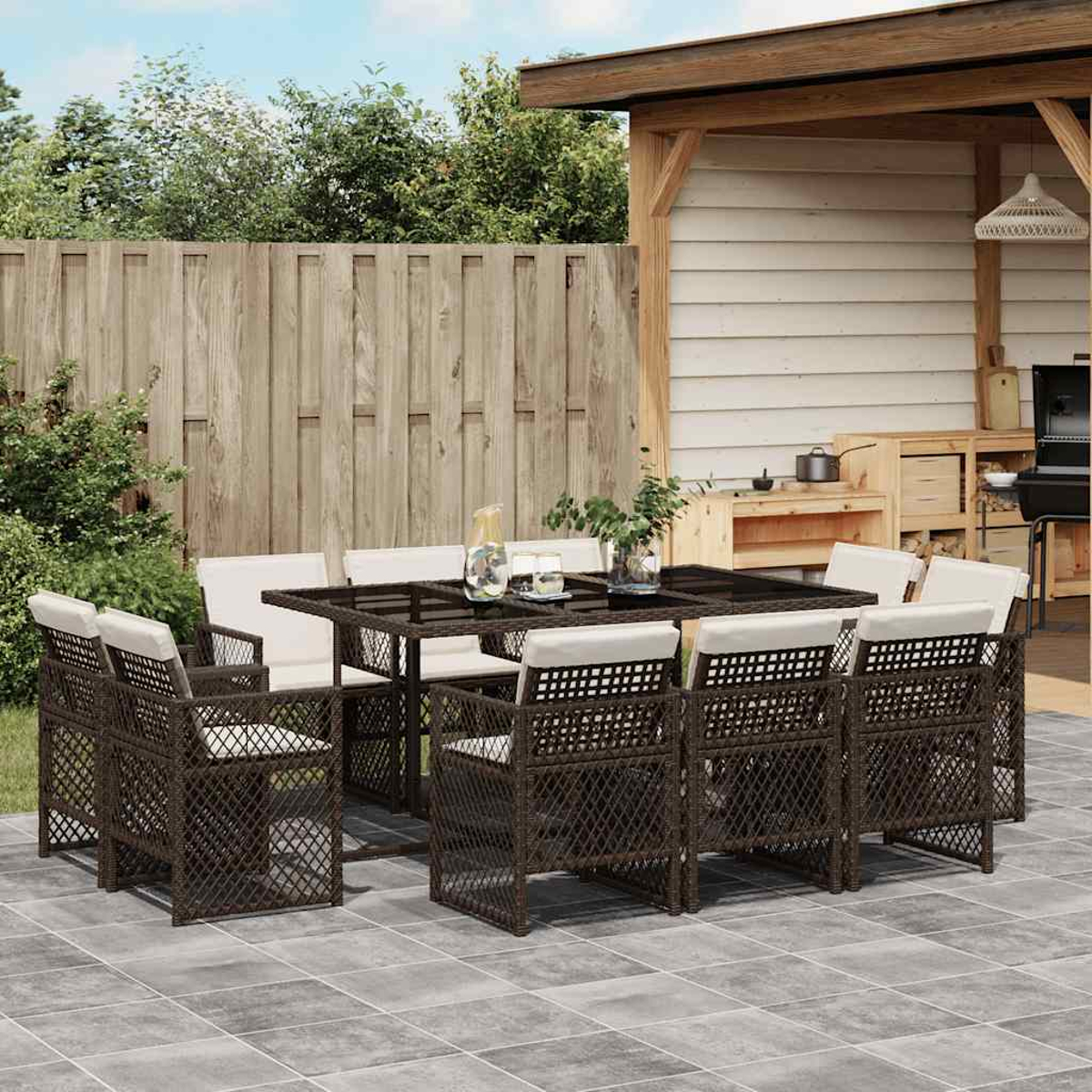 Gartentischgruppe mit acht braunen Rattanstühlen und einer Glasplatte, auf gepflastertem Hof.