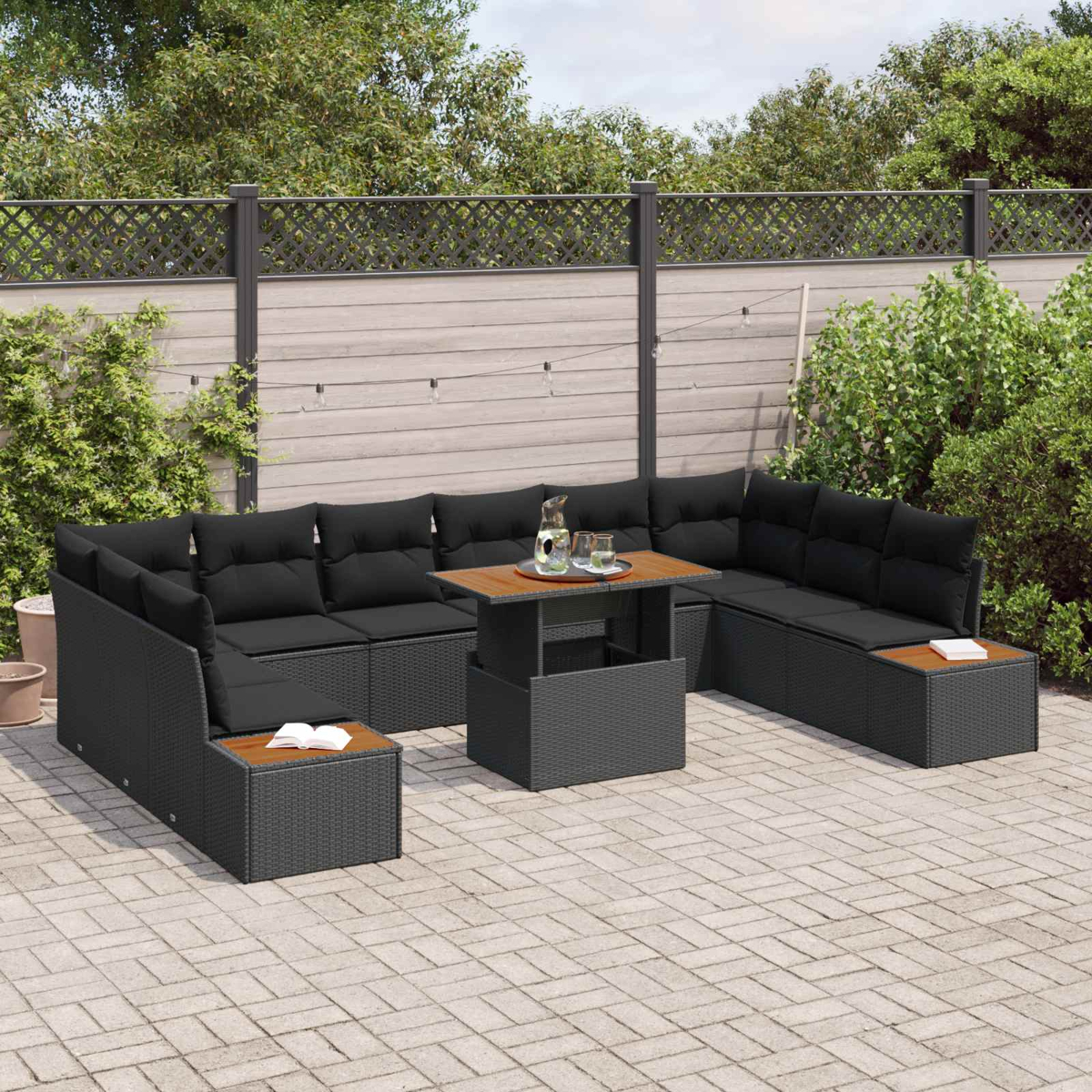 Ein schwarzes Gartenmöbel-Set mit Sofa und Tisch auf einer gepflasterten Terrasse.