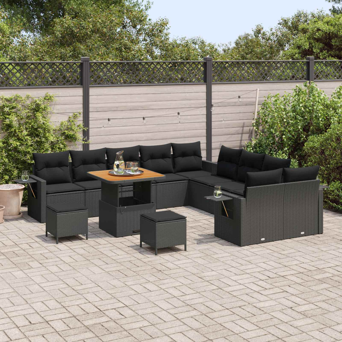 Ein schwarzes Outdoor-Loungeset mit Sofa, Tisch und Hockern auf einer gepflasterten Terrasse.